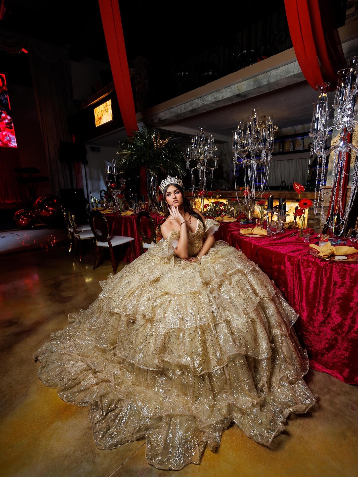Quinceañera con vestido dorado en escenario rojo
